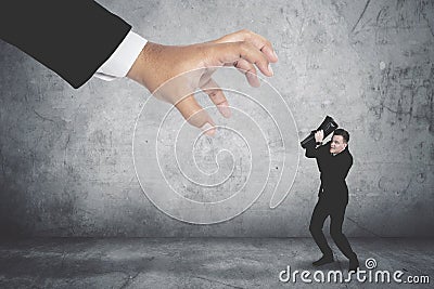 Terrifying businessman covering his face being attacked by a giant hand Stock Photo