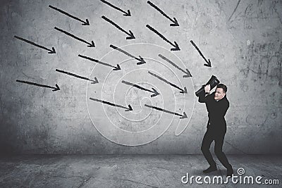 Terrifying businessman covering his face being attacked by arrows Stock Photo