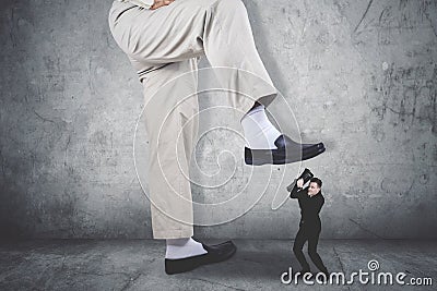Terrifying businessman covering his face being attacked by a giant feet Stock Photo