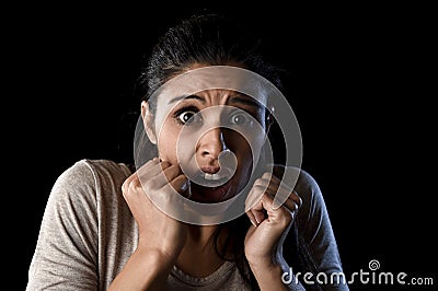 Terrorized and horrified woman desperate and scared isolated on black Stock Photo