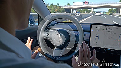 CLOSE UP Unrecognizable man tentatively lets go of the steering wheel of a Tesla Editorial Stock Photo