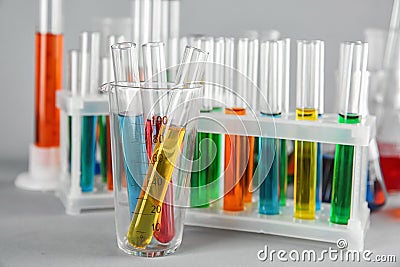 Test tubes with colorful liquids in beaker on table Stock Photo