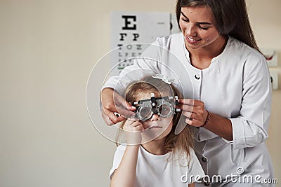 Testing what`s better for his eyes. Doctor checking little girl sight and tuning the phoropter Stock Photo