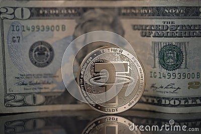 Tether USDT cryptocurrency physical coin placed next to twenty dollars bill on the reflective surface Editorial Stock Photo
