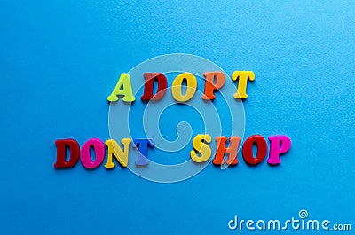 Text adopt don`t shop from plastic colored letters on blue paper background Stock Photo