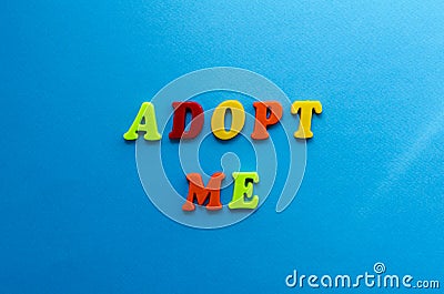 Text adopt me from plastic colored letters on blue paper background Stock Photo