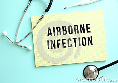 The text AIRBORNE INFECTION is written in a yellow pad that lies next to the stethoscope on a blue background. Stock Photo