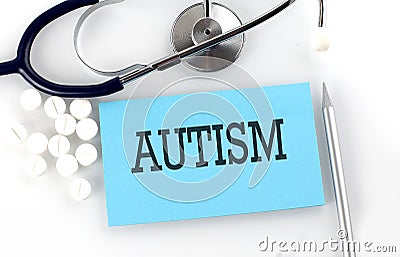 Text AUTISM on a table with a stethoscope,pills and pen, medical concept Stock Photo
