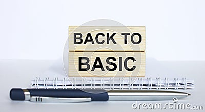 The text BackTo Basic on a bar of jenga wood, lying on a Notepad with a metal blue pen Stock Photo