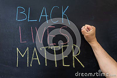 The text Black lives matter, on a chalkboard. A man`s fist against a chalkboard Editorial Stock Photo