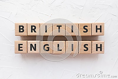 Text BRITISH ENGLISH on wooden cubes on white putty background. Learning languages. Stock Photo