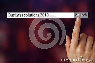 The text in the browser shows `Business solutions 2019`.A woman hand shows the terms you should investigate in 2019. Stock Photo