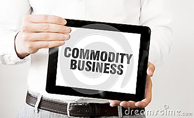 Text COMMODITY BUSINESS on tablet display in businessman hands on the white background. Business concept Stock Photo