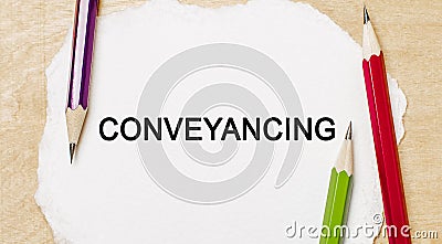 Text Conveyancing on a white notepad with pencils on a wooden background. Business concept Stock Photo