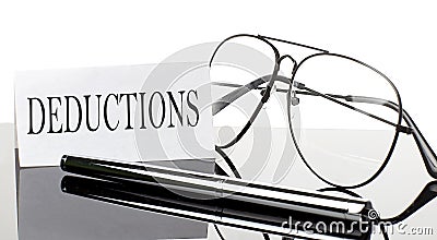 Text DEDUCTIONS on white sticker paper on light background with pen and glasses. Business concept Stock Photo