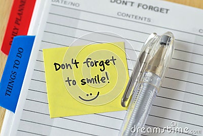 Text don`t forget to smile written on a sticky note over an agen Stock Photo