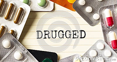 Text DRUGGED on a white background. Nearby are various medicines. Medical concept Stock Photo