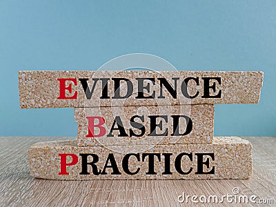 Text EBP Evidence-based practice concept on brick blocks. Beautiful blue background, wooden table. Stock Photo