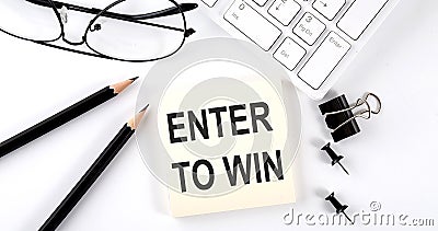 Text ENTER TO WIN on the sticker with keyboard , pencils and office tools Stock Photo