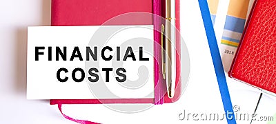 Text FINANCIAL COSTS on white card lying on notepad on office desk. Financial concept Stock Photo