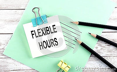 Text FLEXIBLE HOURS on the short note with pencils on the wooden background Stock Photo