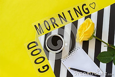 Text Good morning, coffee, yellow rose, notebook for text on stylish black and white napkin on yellow background. Minimal style Stock Photo