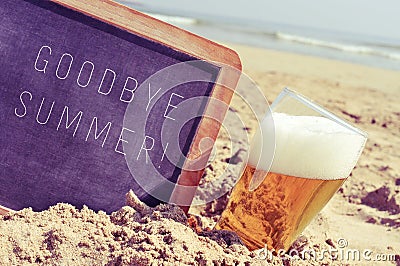 Text goodbye summer in a chalkboard and a glass of beer on the b Stock Photo