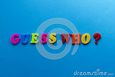 Text guess who? from plastic colored letters on blue paper background Stock Photo