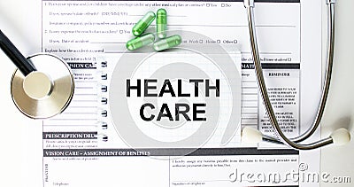 Text Health Care in a notebook on medical forms with a phonendoscope and green pills Stock Photo