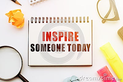 Text INSPIRE SOMEONE TODAY in notebook on white table with office tools Stock Photo