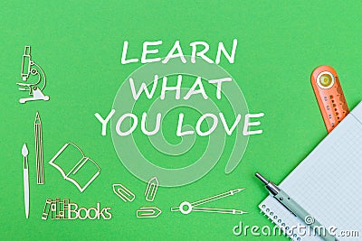 Text learn what you love, school supplies wooden miniatures, notebook with ruler, pen on green backboard Stock Photo