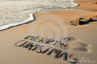 Text merry christmas in the sand of a beach Stock Photo