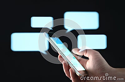 Text messages in cellphone screen with abstract hologram speech bubbles. Instant messaging app. Texting, group chat, sexting. Stock Photo