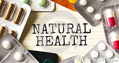 Text NATURAL HEALTH on a white background. Nearby are various medicines. Medical concept Stock Photo