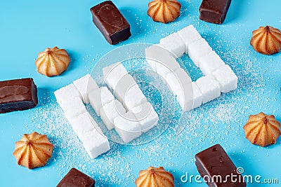 Text No is lined with sugar cubes with sweets and cookies. Harm to the health of sweet and rejection of sucrose Stock Photo