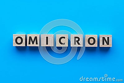Text OMICRON on wooden cubes on bright blue background. Medicine concept Stock Photo