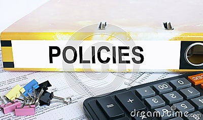 Text Policies on the folder that is located on the financial reports with calculator and stationery clips Stock Photo