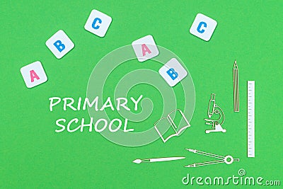 Text primary school, from above wooden minitures school supplies and abc letters on green background Stock Photo