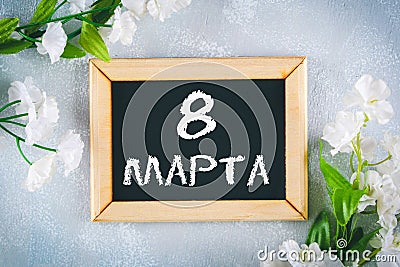 Text in Russian: March 8. Black chalkboard and white flowers. International Women`s Day. Stock Photo