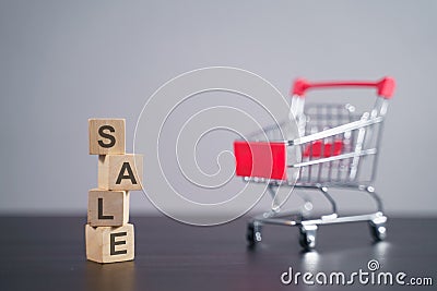 Text `SALE` on wooden cube with shopping cart over background Stock Photo