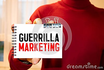 Text sign showing guerilla marketing. The text is written on a small wooden blackboard Stock Photo