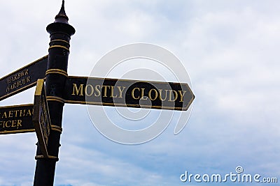 Text sign showing Mostly Cloudy. Conceptual photo Shadowy Vaporous Foggy Fluffy Nebulous Clouds Skyscape Road sign on Stock Photo
