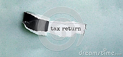 The text tax return appearing behind torn green paper. Stock Photo