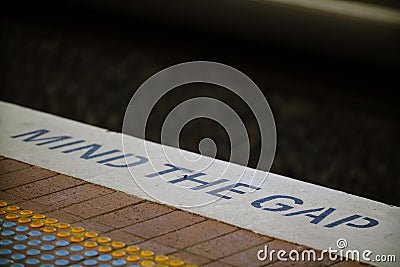 Text warning MIND THE GAP on stone platform on train or metro station Editorial Stock Photo