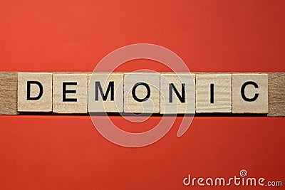 Text the word demonic from gray wooden small letters Stock Photo