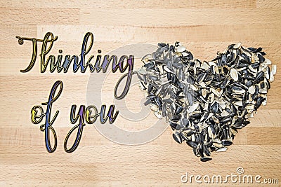 Thinking of you - card. Heart lined with husks of sunflower seeds on a background of beech wood. Stock Photo