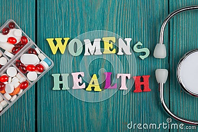 Text & x22;Women& x27;s health& x22; of colored wooden letters, stethoscope and pills Stock Photo