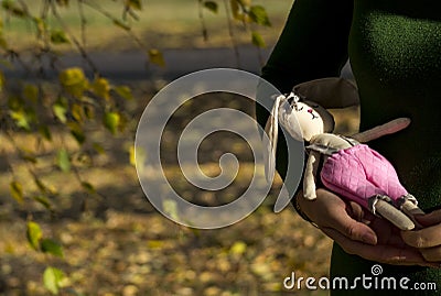 Textile hare toy in multi-colored clothes lying on a woman`s hand. Registration of holidays. Interior fairy doll Stock Photo