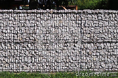 Texture for the background of a backdrop of a freely lying stone supported by a metal mesh. Technology of construction of fences f Stock Photo