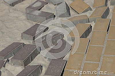 Texture of brown stone bricks of paving slabs on an unfinished road in gray sand Stock Photo